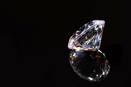 One shiny diamond on mirror surface against black background, closeup. Space for textの写真素材