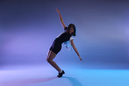 Teenage girl in tap shoes dancing on color background