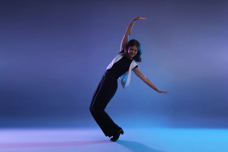 Teenage girl in tap shoes dancing on color background