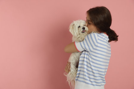 Happy teenage girl with dog on pink background, space for textの写真素材