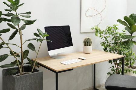Biophilic interior design. Stylish workplace with computer and houseplants in officeの写真素材