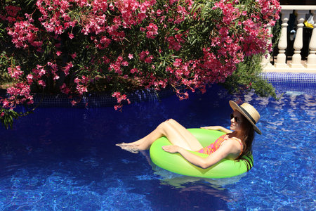 Girl on inflatable ring in swimming pool outdoors on sunny day