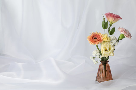 Beautiful flowers in vase on white cloth, space for textの写真素材