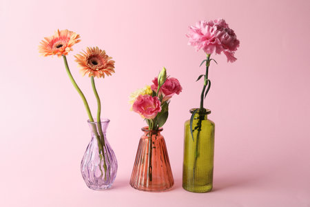 Beautiful flowers in glass vases on pink backgroundの写真素材