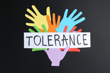 Card with word Tolerance and colorful paper hands on black background, flat lay