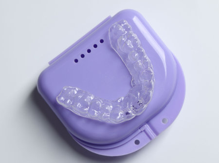 One clear aligner and retainer case on light gray background, top view