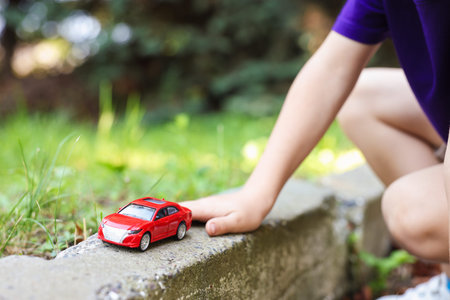 Little boy playing with toy car outdoors, closeup