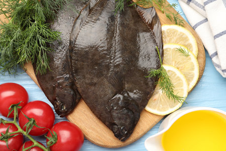 Fresh raw flounder fish and ingredients on light blue wooden table, flat lay. Seafood