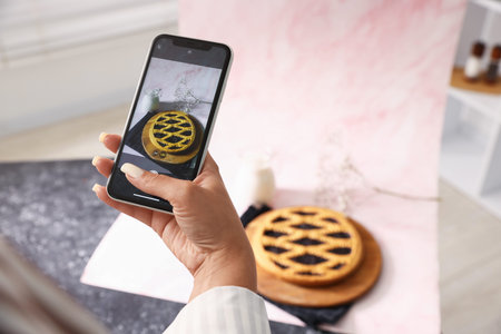 Woman taking picture of tasty pie and milk in studio, selective focus. Professional food photographyの写真素材