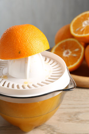 Making juice. Juicer and fresh oranges on wooden table, closeup
