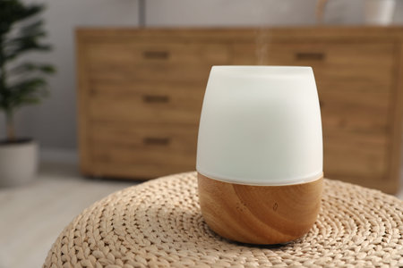 Modern aroma lamp on wicker surface indoors. Space for text