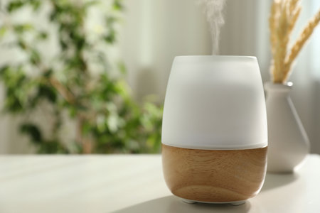 Modern aroma lamp on light table indoors. Space for text