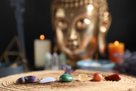 Chakra gemstones on table with candles and Buddha figure, selective focus