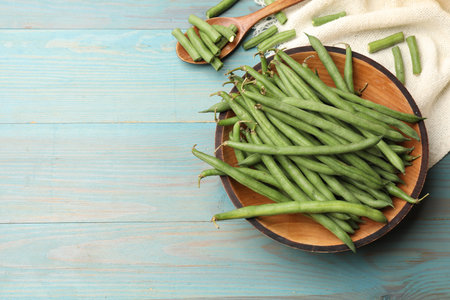 Many raw green beans on blue wooden table, flat lay.