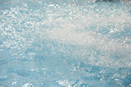Splashes in swimming pool on sunny day. Summer vacation