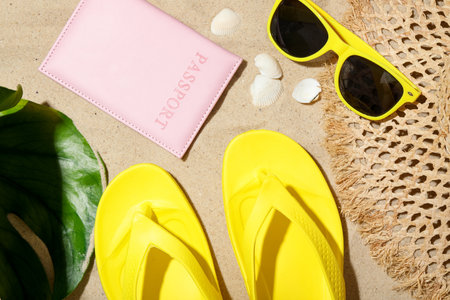 Time for summer vacation. Passport, green leaf and beach accessories on sand, flat layの写真素材