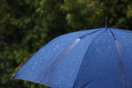 Blue umbrella under heavy rain outdoors, closeup