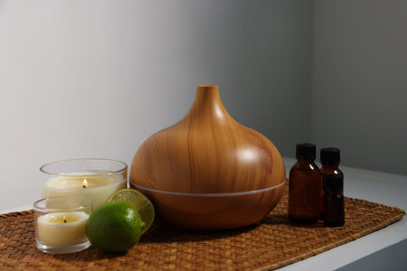 Spa composition with aroma oil diffuser, burning candles and cosmetic products on table indoors