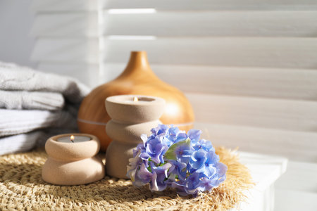 Spa composition with burning candles, aroma oil diffuser and flowers on white table indoors, closeup