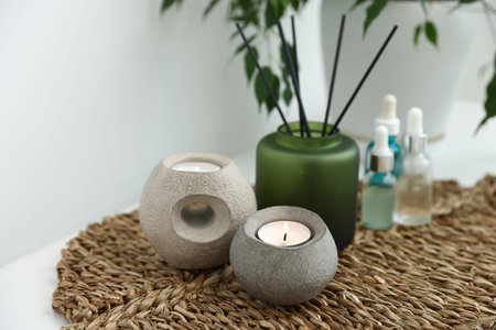 Spa composition with burning candles and reed air freshener on table indoors, closeup