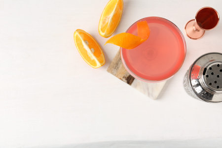Martini cocktail with garnish, slices of orange and bartender equipment on white table, flat lay. Space for textの写真素材