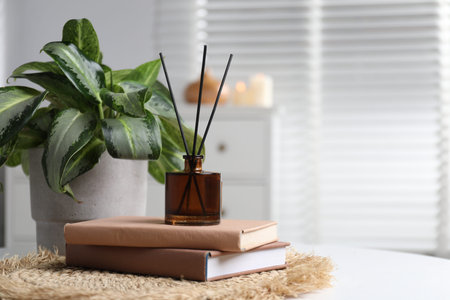 Spa composition with reed air freshener, books and houseplant on white table indoors, closeup. Space for textの写真素材