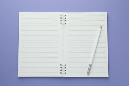 Open notepad and white pencil on violet background, top view. Space for text
