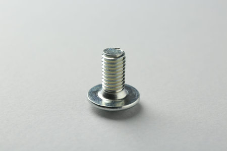 One metal bolt on light grey background, closeup. Hardware tool