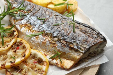 Tasty roasted mackerel with spices and potatoes on gray table, closeup. Homemade seafood dish