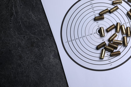 Metal bullets and shooting target on grey table, top view. Space for text