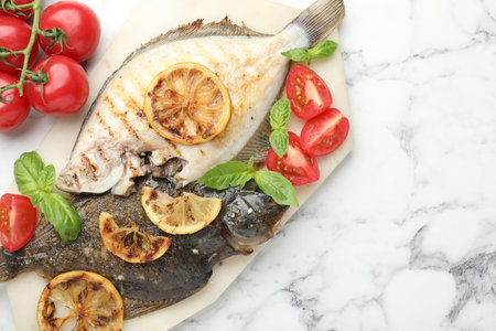 Homemade seafood dish. Tasty roasted flounder fish served with tomatoes, basil and lemon slices on...