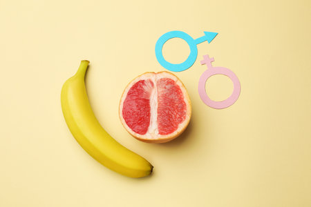 Sex education. Banana, grapefruit, paper female and male gender symbols on beige background, flat layの写真素材