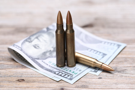 Bullets and dollars on wooden table, closeup