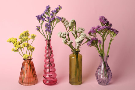 Beautiful flowers in glass vases on pink background