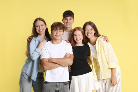 Portrait of happy teenage friends on yellow backgroundの写真素材