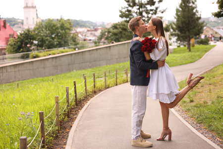 Marriage proposal. Man kissing his beloved with bouquet of roses on engagement day outdoors. Space for textの写真素材
