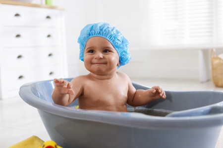 Cute little baby in cap bathing at home