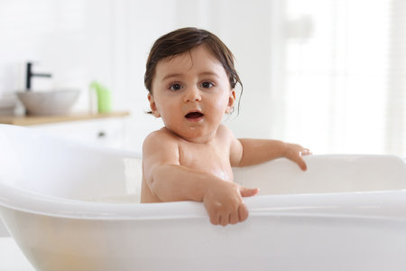 Cute little baby bathing in tub at homeの写真素材