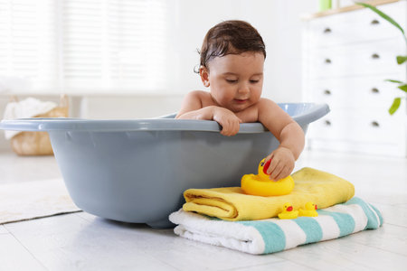 Cute little baby bathing in tub at home