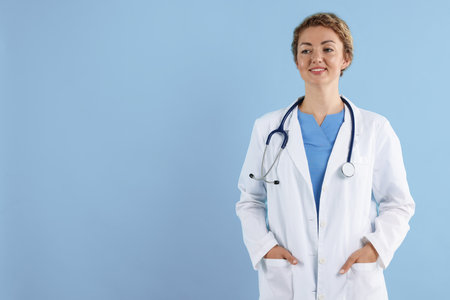 Portrait of professional pediatrician with stethoscope on light blue background. Space for textの写真素材
