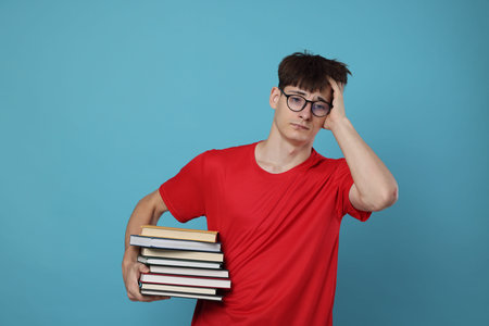 Exam result. Worried student with books on light blue background