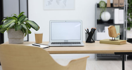 Stylish workplace with laptop, coffee and stationery on wooden table in officeの写真素材