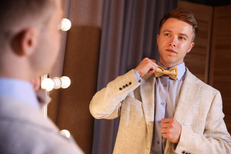Handsome man getting ready near mirror indoorsの写真素材