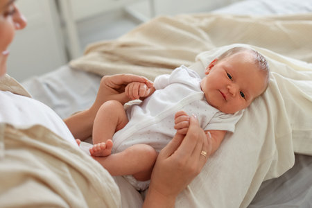 Mother with her newborn baby on bed at home, closeup