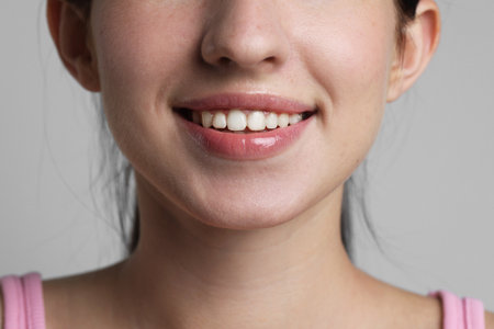 Smiling woman after dental aligners treatment on grey background, closeupの写真素材