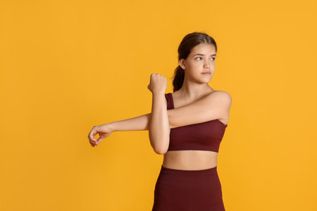Teenage girl in sportswear stretching on orange background, space for textの写真素材