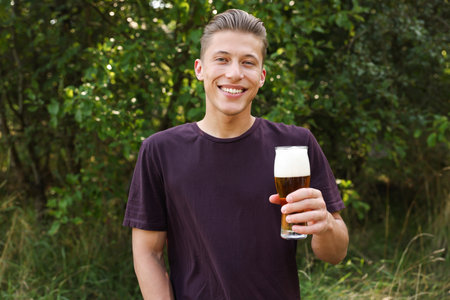 Young man with glass of beer outdoors
