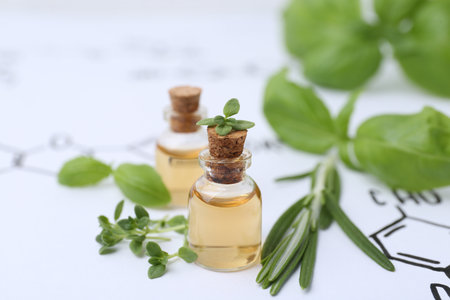 Different herbs and bottles of cosmetic products on paper with chemical formulas, closeupの写真素材