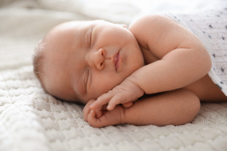 Cute newborn baby sleeping on bed indoors