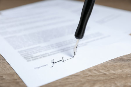 Signing notary document with fountain pen at wooden table, closeupの写真素材
